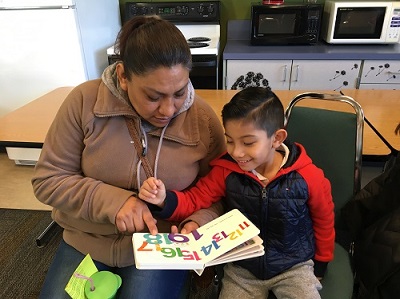 Adult and child reading together at a family literacy event